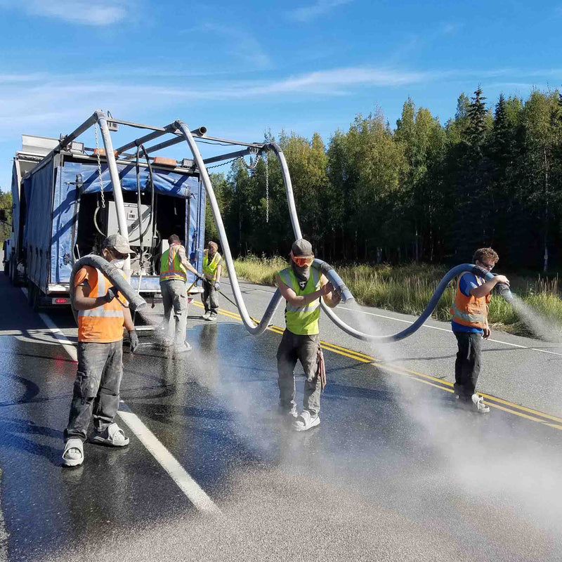 Workers spraying road with drop hoses attached to the AST GMP 500 dispensing system