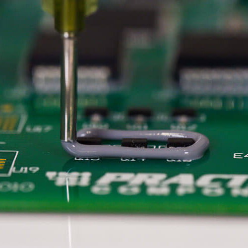 Close-up of a handheld valve precisely encapsulating electronic components on a circuit board